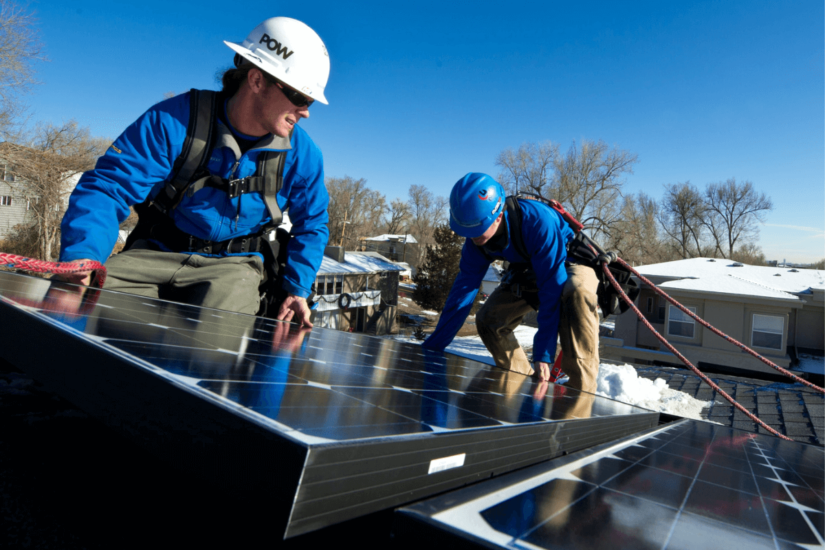 Afschaffing btw op zonnepanelen Twee installateurs installeren een zonnepaneel.