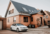 Een witte auto staat geparkeerd voor een huis op de oprit.