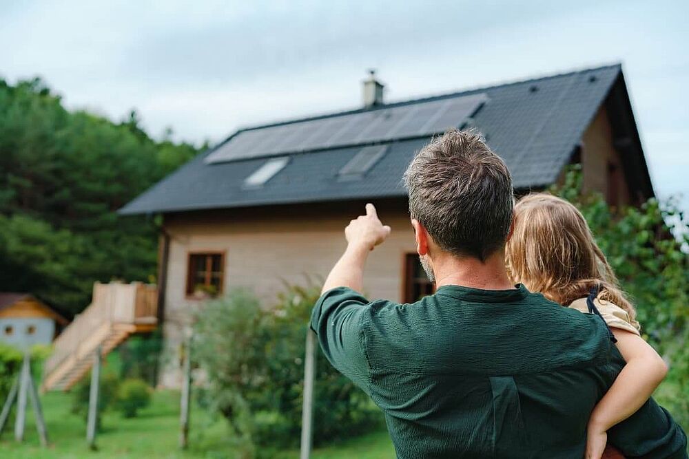 Woningeigenaren kijken naar hun huis waar zonnepanelen op het dak liggen.