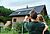 Woningeigenaren kijken naar hun huis waar zonnepanelen op het dak liggen.